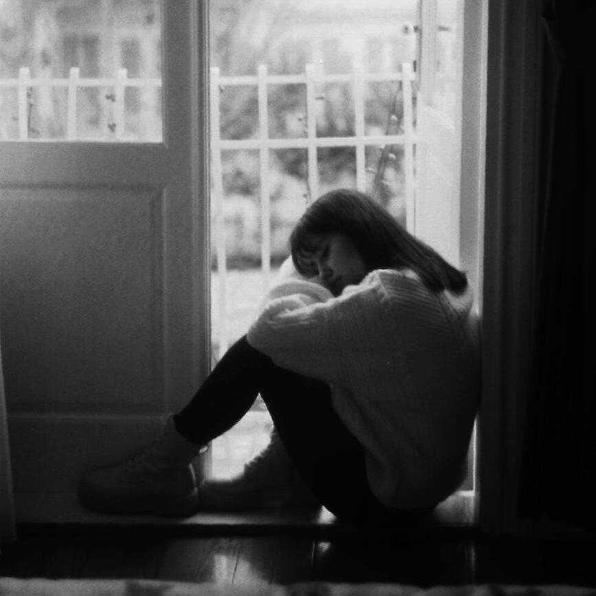 sad woman sitting in doorway of balcony